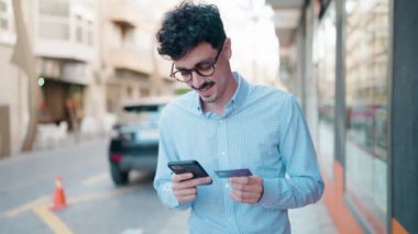 Genç İspanyol adam akıllı telefon ve kredi kartı kullanıyor.