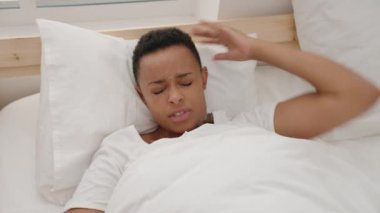 Afro-Amerikalı kadın yatakta uzanıyor. Yatak odasında kâbus görüyor.
