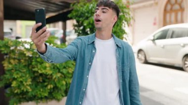 Young hispanic man smiling confident having video call at street
