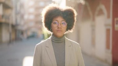 Sokakta ciddi bir ifadeyle duran Afrikalı Amerikalı kadın.