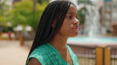 Afro-Amerikalı kadın parkta kendinden emin bir şekilde gülümsüyor.