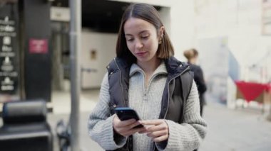 Genç ve güzel İspanyol kadın akıllı telefon kullanıyor. Sokakta ciddi bir ifadesi var.