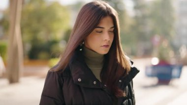 Young hispanic woman standing with serious expression at street