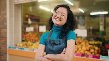 Young chinese woman employee smiling confident standing with arms crossed gesture at fruit store
