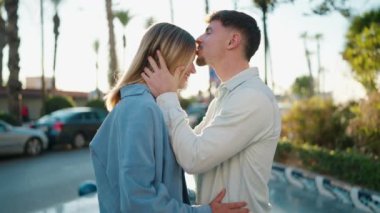 Young couple kissing and hugging each other standing at street