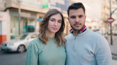 Genç çift gülümsüyor. Birbirlerine sarılıyorlar. Sokakta duruyorlar.