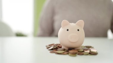 Genç Afrikalı Amerikalı kadın evdeki domuz kumbarasına para sokuyor.