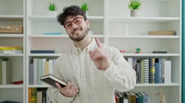 Genç İspanyol öğrenci elinde kütüphane üniversitesini gösteren bir kitap tutuyor.