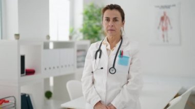Middle age woman wearing doctor uniform standing at clinic