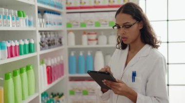 Young african american woman pharmacist using touchpad working at pharmacy