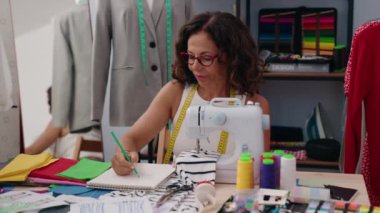 Orta yaşlı kadın terzi elbise fabrikasında kendine güvenen çizimler yapıyor.