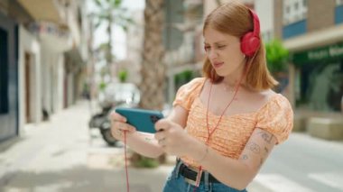 Genç kızıl saçlı kadın gülümsüyor. Sokakta oyun oynarken kendine güveniyor.