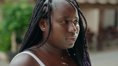 Afro-Amerikalı kadın gülümsüyor. Kendinden emin bir şekilde caddeye bakıyor.