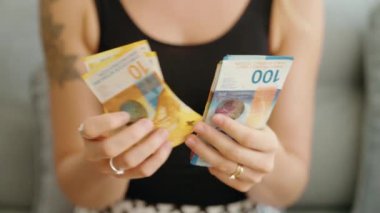 Genç bir kadın evde İsviçre banknotlarını sayıyor.