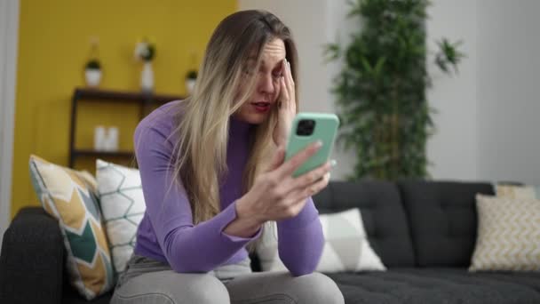 Jong Blond Vrouw Met Behulp Van Smartphone Zitten Bank Thuis — Stockvideo