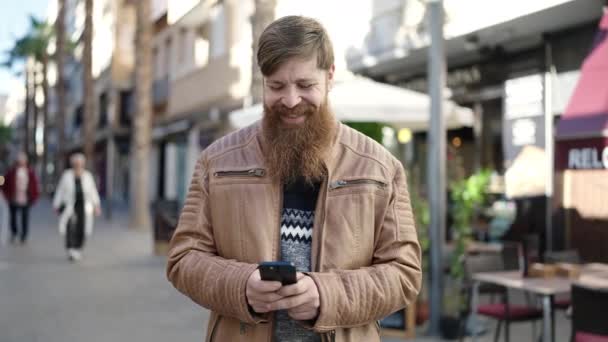 Молодой Рыжий Мужчина Улыбается Уверенно Используя Смартфон Террасе Кафе — стоковое видео