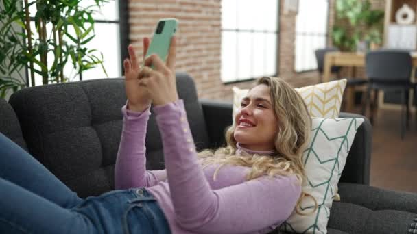 Junge Blonde Frau Mit Smartphone Hause Auf Sofa Liegend — Stockvideo