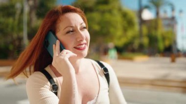 Young redhead woman smiling confident talking on the smartphone at park
