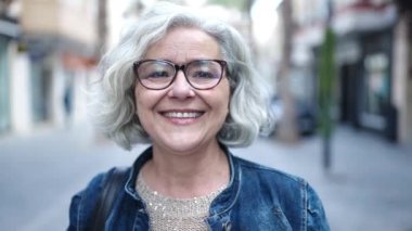 Middle age woman with grey hair smiling confident at street