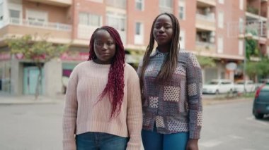 Two african american women smiling confident standing with arms crossed gesture at street