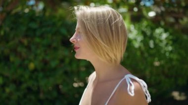 Parkta kendinden emin gülümseyen genç sarışın kadın.