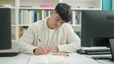 Kütüphanede sırtı ağrıyan genç İspanyol öğrenci notlar yazıyor.