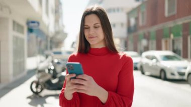 Sokakta akıllı telefon kullanan kendine güvenen genç bir kadın.