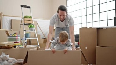 Baba ve oğul yeni evlerinde köpük karton kutuyla oynuyorlar.