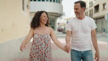 Kadın ve erkek, sokakta yürürken gülümsüyor.