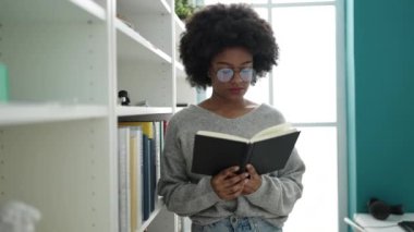African american woman student reading book doing silence gesture at library university