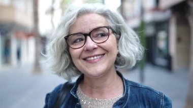 Middle age woman with grey hair smiling confident at street
