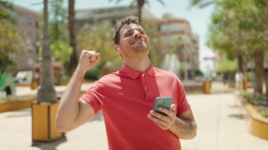 Young hispanic man smiling confident listening to music at park