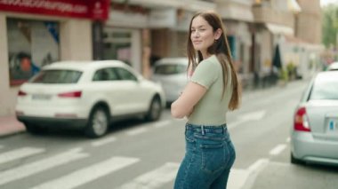 Sokakta kollarını kavuşturmuş genç ve güzel bir kadın.