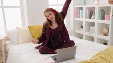 Genç ve güzel İspanyol kadın dans ediyor ve yatak odasında oturmuş müzik dinliyor.