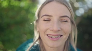 Young blonde woman smiling confident showing braces at park