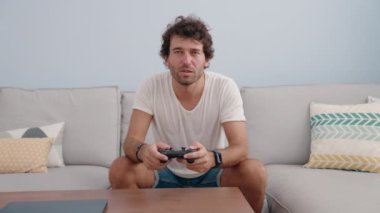 Evdeki kanepede oturan İspanyol asıllı genç oyun oynuyor.