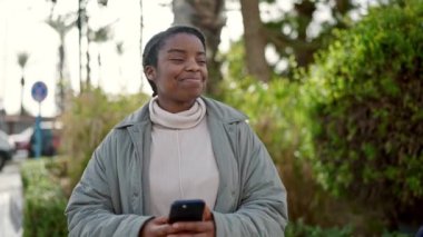 Afrikalı Amerikalı kadın parkta akıllı telefondan video kaydediyor.