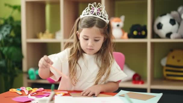 愛らしいブロンド女の子就学前学生身に着けています王女クラウン描画のために紙に幼稚園 — ストック動画