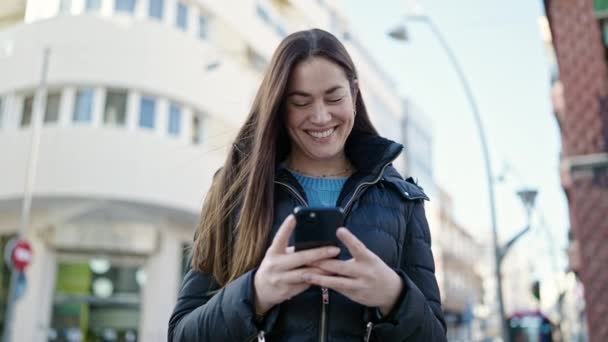 若い白人女性が路上でスマートフォンを使って自信を持って笑っています — ストック動画