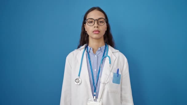 年轻美丽的惊慌失措的女医生面带微笑 自信地站在孤独的蓝色背景之上 — 图库视频影像
