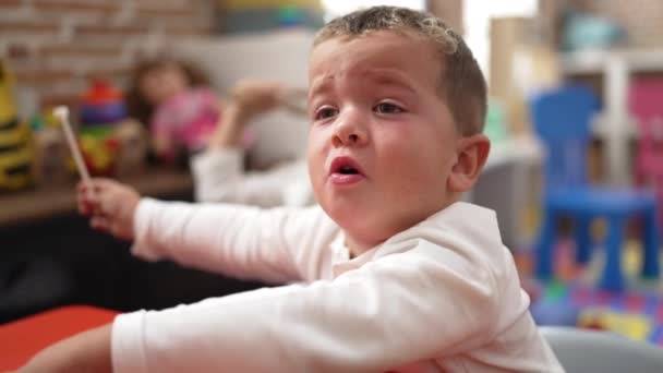 可爱的女孩和男孩坐在桌子上 在幼儿园打架 — 图库视频影像