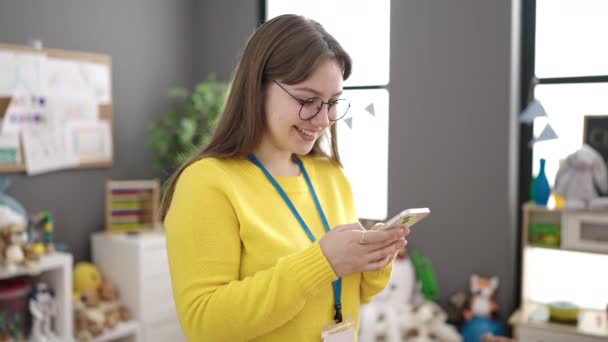 Young Blonde Woman Preschool Teacher Smiling Confident Using Smartphone Kindergarten — 图库视频影像