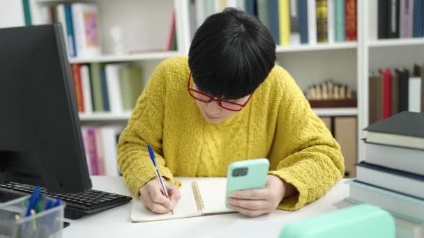 Young Chinese Woman Student Using Smartphone Writing Notebook Library University — Vídeo de Stock