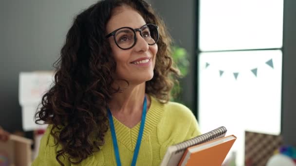 Middle Age Hispanic Woman Preschool Teacher Smiling Confident Holding Books — Stok video