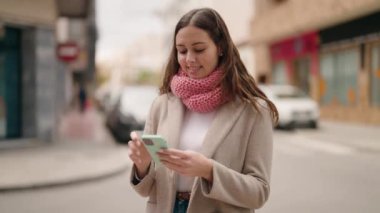 Sokakta akıllı telefon kullanan kendine güvenen genç bir kadın.