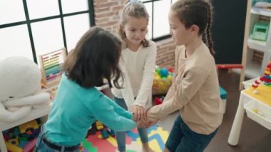 Group of kids smiling confident standing with hands together at kindergarten