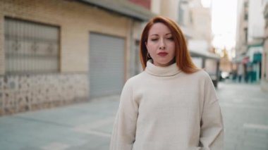 Caddede kendine güvenen genç kızıl saçlı kadın gülümsüyor