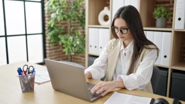 Genç ve güzel İspanyol iş kadını ofiste dizüstü bilgisayar kullanıyor.