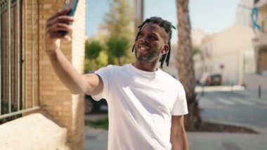 Afro-Amerikalı kadın sokakta akıllı telefon kullanarak kendine güveniyor.