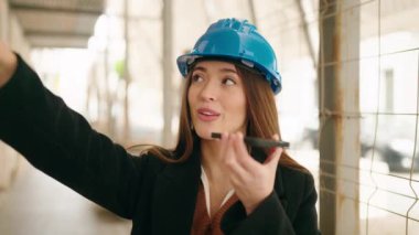 Young hispanic woman architect talking on the smartphone at street